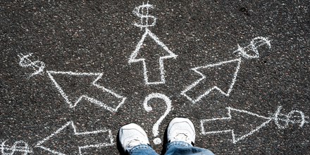 Bird's eye view of a person's feet on sidewalk, surround by five arrows, each pointing to a dollar sign, symbolizing making a choice with money.